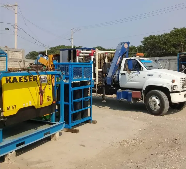 Compresor Kaeser M57 y rack de cilindros junto a camión grúa