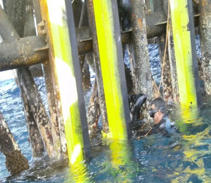 Buzo trabajando junto a las piernas de una plataforma marina